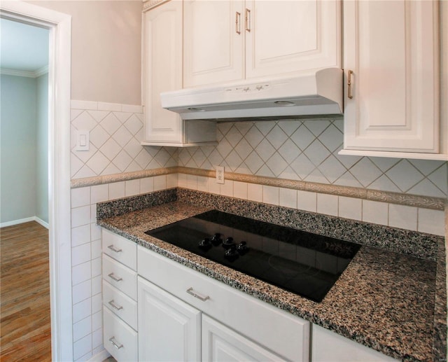 kitchen featuring white cabinetry, dark stone countertops, black electric cooktop, and crown molding