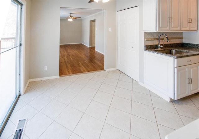 kitchen featuring ceiling fan, sink, dark stone counters, decorative backsplash, and light tile patterned flooring