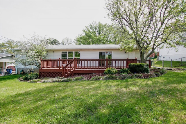rear view of property with a lawn, a wooden deck, and fence
