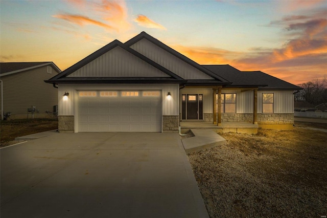 view of front of property featuring stone siding, concrete driveway, board and batten siding, and an attached garage