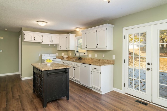 kitchen with white appliances, dark wood-type flooring, a kitchen island, and white cabinets