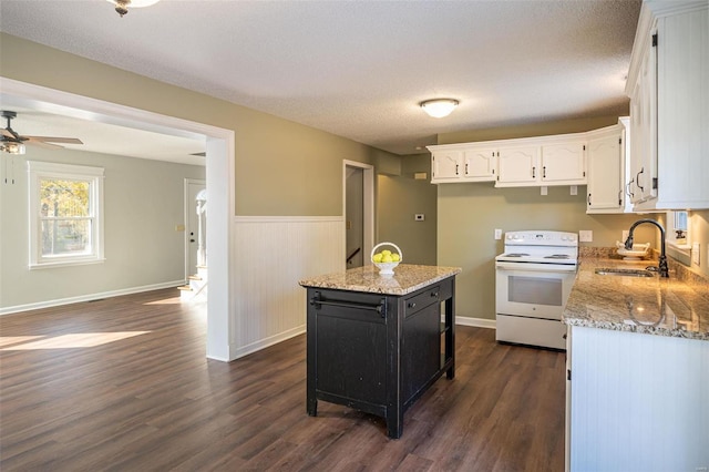 kitchen with dark wood-type flooring, light stone countertops, a center island, white electric stove, and white cabinets