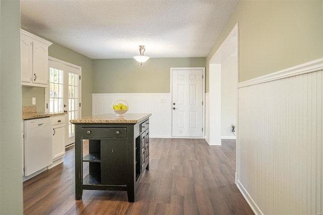 kitchen with dishwasher, a kitchen island, a textured ceiling, white cabinets, and dark hardwood / wood-style floors