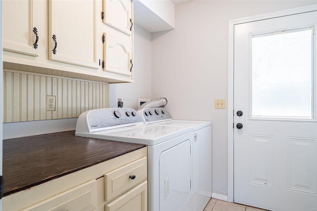 washroom featuring light tile patterned flooring, independent washer and dryer, a healthy amount of sunlight, and cabinets