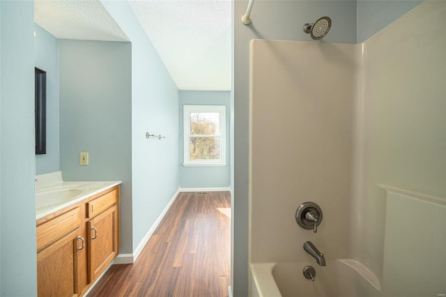 bathroom with vanity, a textured ceiling, wood-type flooring, and bathing tub / shower combination