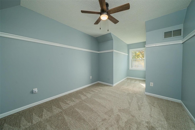 carpeted spare room with a textured ceiling, vaulted ceiling, and ceiling fan