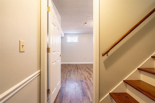 staircase with a textured ceiling and wood-type flooring