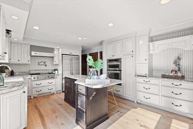 kitchen with a kitchen breakfast bar, light hardwood / wood-style flooring, stainless steel appliances, a center island, and white cabinetry