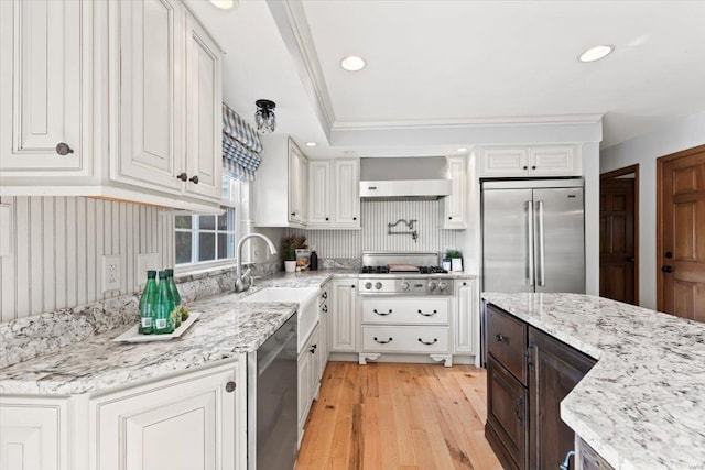 kitchen featuring white cabinets, ornamental molding, sink, light hardwood / wood-style floors, and stainless steel appliances