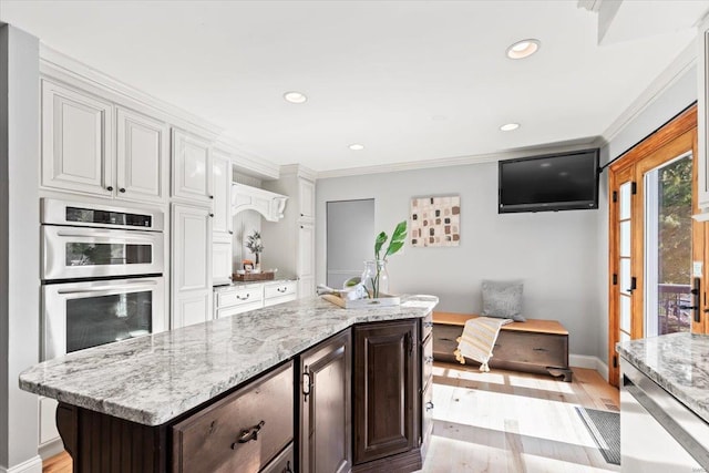 kitchen with light hardwood / wood-style floors, white cabinets, dark brown cabinets, and stainless steel double oven