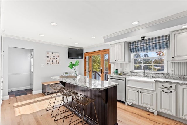 kitchen featuring a breakfast bar, light hardwood / wood-style flooring, dishwasher, and plenty of natural light