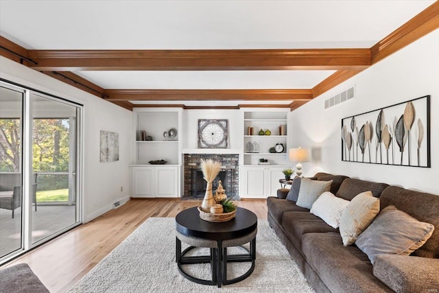 living room with light hardwood / wood-style floors, beam ceiling, and a brick fireplace