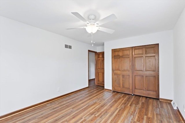 unfurnished bedroom with hardwood / wood-style floors, a closet, and ceiling fan