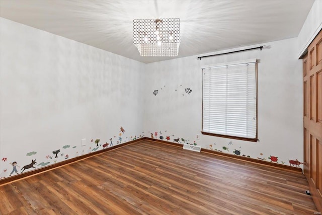 spare room with a notable chandelier and dark hardwood / wood-style flooring