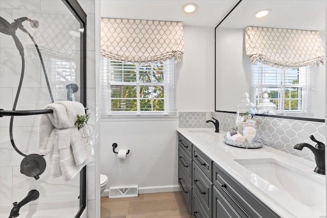 bathroom featuring wood-type flooring, backsplash, an enclosed shower, toilet, and vanity