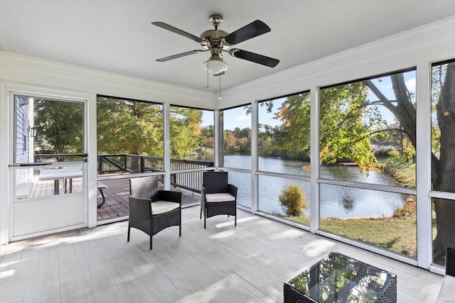 sunroom / solarium featuring a healthy amount of sunlight, a water view, and ceiling fan