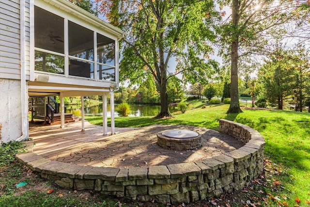 view of patio / terrace with an outdoor fire pit, a water view, and a sunroom