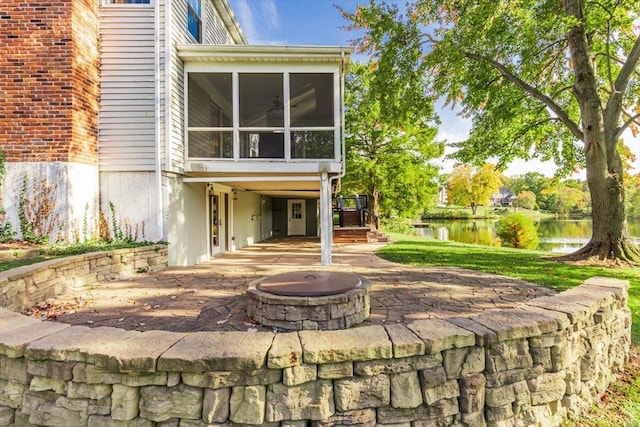 rear view of house with a water view, a patio, a fire pit, and a sunroom