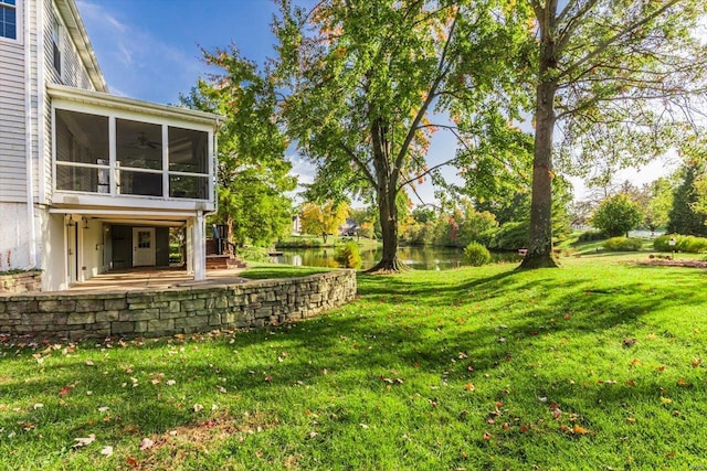 view of yard featuring a water view, a patio area, and a sunroom