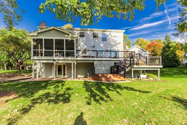 back of property with a patio area, a wooden deck, a lawn, and a sunroom