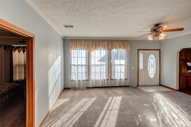 carpeted foyer entrance with a wealth of natural light, a textured ceiling, and ceiling fan