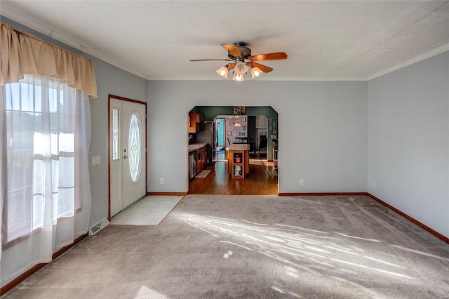 foyer with ceiling fan, carpet, a textured ceiling, and ornamental molding