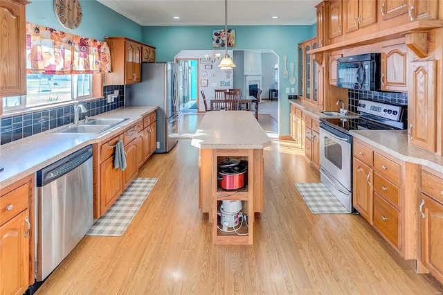 kitchen featuring backsplash, sink, a center island, light wood-type flooring, and appliances with stainless steel finishes