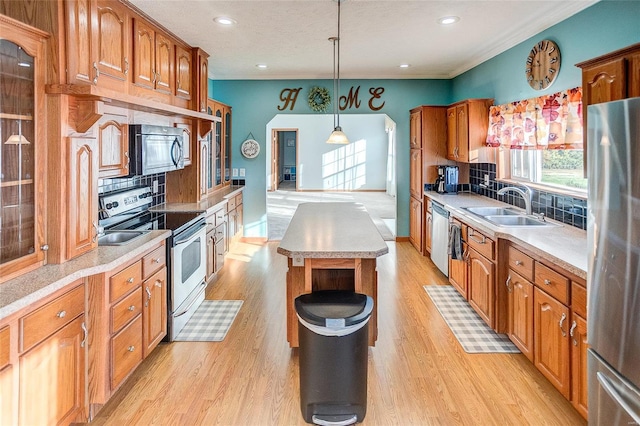 kitchen with decorative backsplash, hanging light fixtures, sink, appliances with stainless steel finishes, and light hardwood / wood-style floors