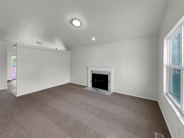 unfurnished living room with dark colored carpet and a high end fireplace