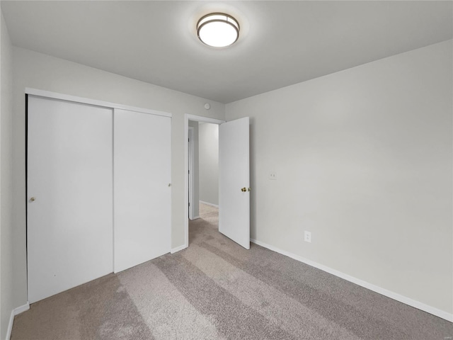 unfurnished bedroom with a closet and light colored carpet