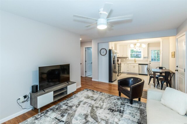 living room with sink, hardwood / wood-style flooring, and ceiling fan with notable chandelier