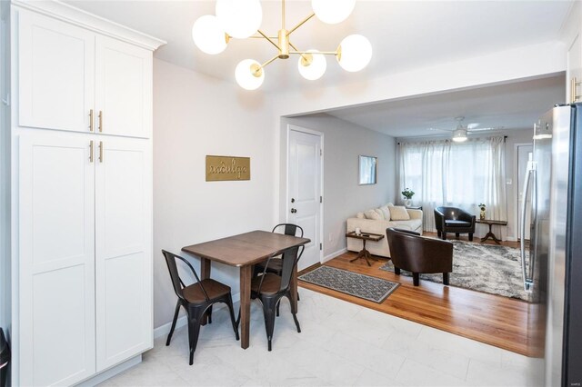 dining area featuring light hardwood / wood-style flooring and ceiling fan with notable chandelier