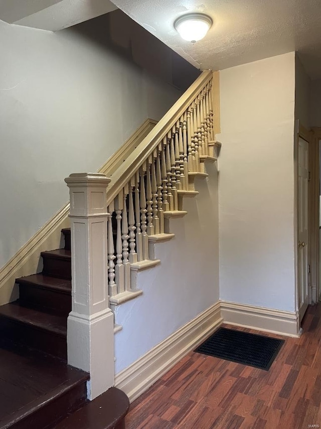 staircase featuring a textured ceiling and hardwood / wood-style floors