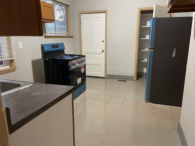 kitchen with black gas range, refrigerator, and light tile patterned floors