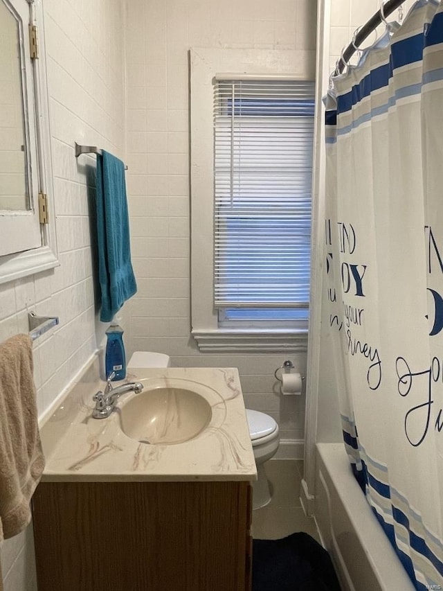 full bathroom featuring toilet, shower / bath combo, vanity, and tile walls