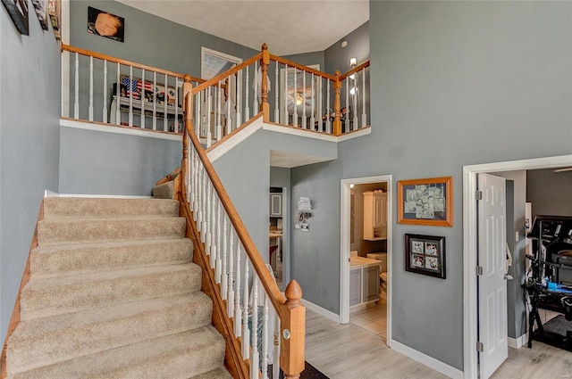 stairs featuring a towering ceiling and wood-type flooring