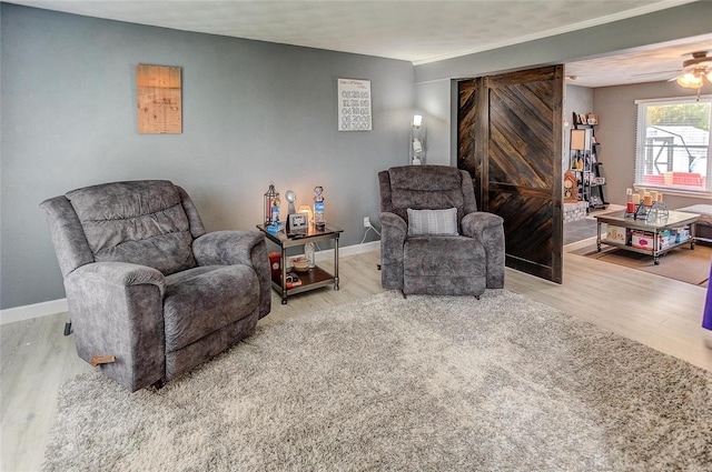 sitting room featuring a barn door, wood-type flooring, and ceiling fan