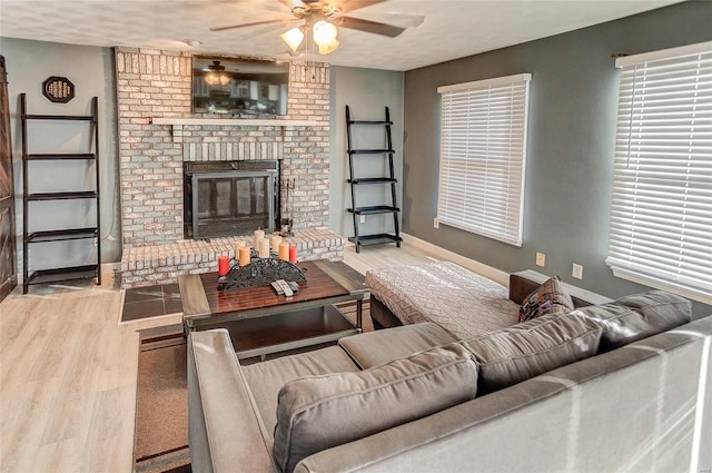 living room featuring ceiling fan, hardwood / wood-style flooring, and a brick fireplace