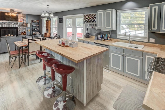 kitchen with a kitchen island, a fireplace, gray cabinetry, decorative light fixtures, and sink