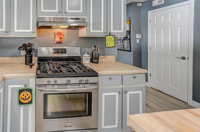 kitchen with white cabinetry, light hardwood / wood-style floors, ventilation hood, and stainless steel gas range oven