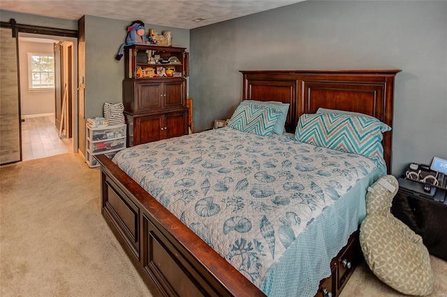 carpeted bedroom featuring a barn door and a textured ceiling