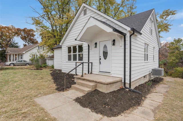 bungalow-style home with a front lawn and central AC unit