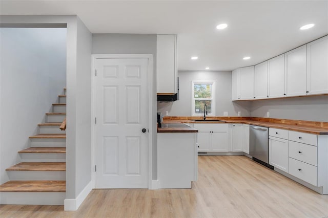 kitchen with wood counters, white cabinets, sink, stainless steel dishwasher, and light wood-type flooring