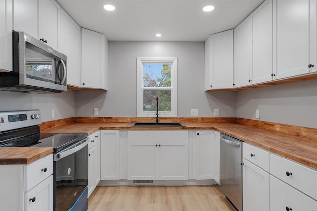 kitchen with white cabinets, appliances with stainless steel finishes, and wooden counters