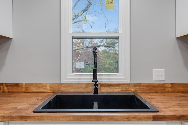 interior details with white cabinetry, sink, and wooden counters