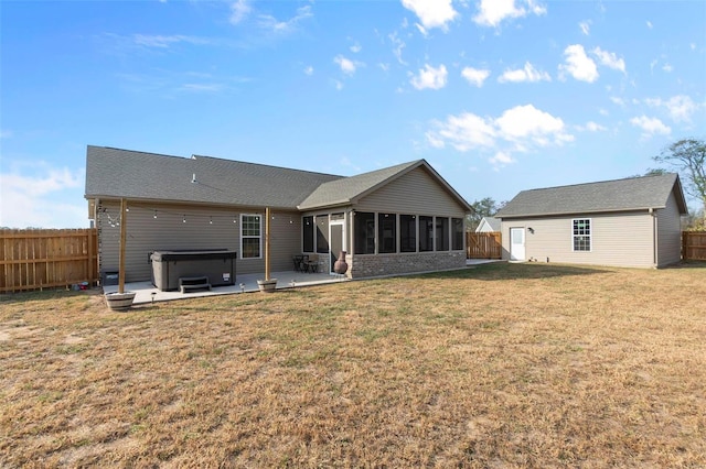 back of property featuring a patio area, a hot tub, a lawn, and a sunroom