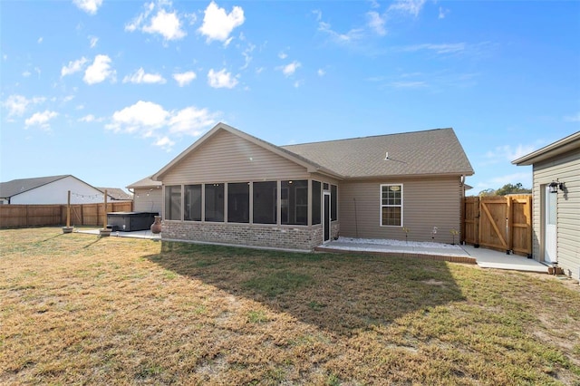 rear view of house featuring a patio, a lawn, and a sunroom