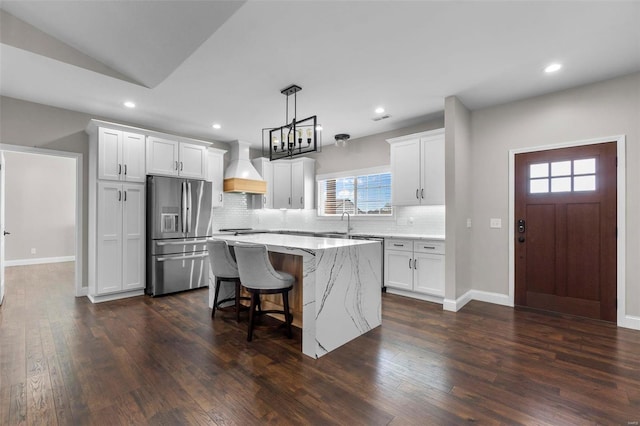 kitchen featuring dark wood-type flooring, stainless steel appliances, a center island, pendant lighting, and premium range hood