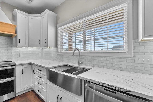 kitchen with a wealth of natural light, custom exhaust hood, appliances with stainless steel finishes, and white cabinetry