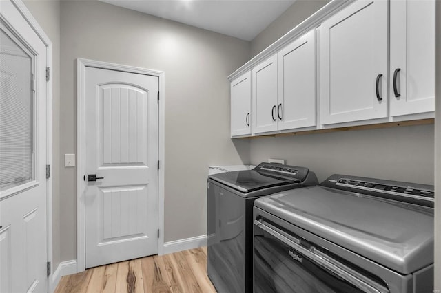 laundry area featuring light hardwood / wood-style floors, cabinets, and washer and clothes dryer